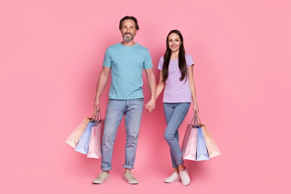 Full-Size-Porträt von zwei positiven idyllischen Partnern halten Arme Boutique-Pakete isoliert auf rosa Hintergrund — Stockfoto