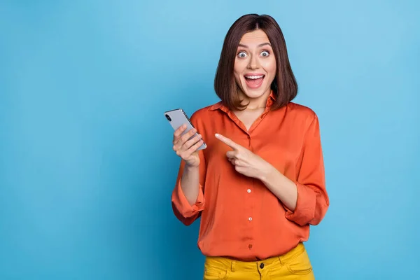 Ritratto di attraente allegra ragazza stupita utilizzando dispositivo dimostrando notizie dei media come isolato su sfondo di colore blu brillante — Foto Stock