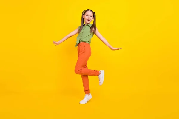 Φωτογραφία από ενθουσιασμένος funky κορίτσι φοιτητής φορούν πράσινο πουκάμισο χαμογελώντας περπάτημα απομονωμένο κίτρινο χρώμα φόντο — Φωτογραφία Αρχείου