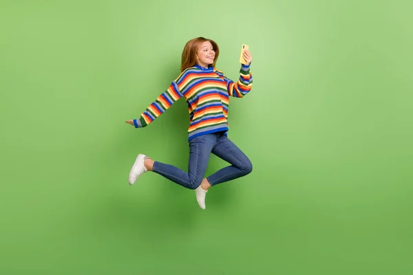 将设备应用与明亮的绿色背景隔离 以全长体形观看迷人而有趣的女孩跳跳 — 图库照片