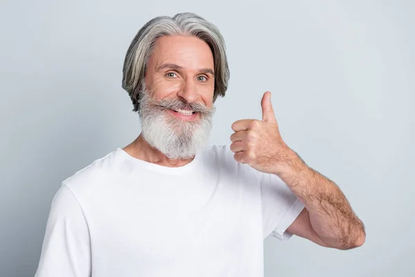 Foto Atraktivní Veselý Muž Důchodce Oblečené Bílé Tričko Ukazující Palec — Stock fotografie