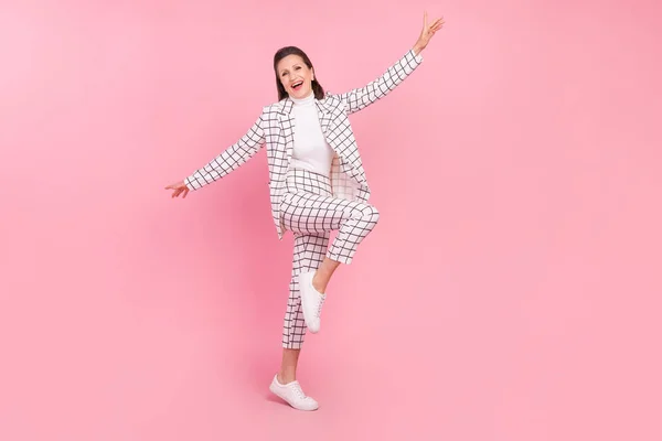 Full size image of cheerful mature lady dancing energetic businesswoman isolated on pink color background.