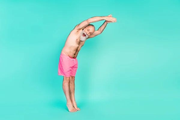 Profile photo of excited funky old man jump pool open mouth wear pink shorts isolated teal color background.
