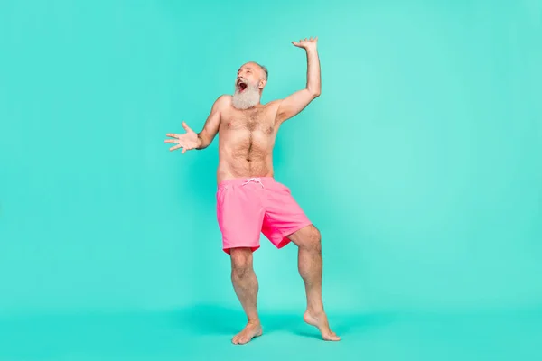 Photo of crazy careless old man dance beach party scream rejoice wear pink shorts isolated turquoise color background.