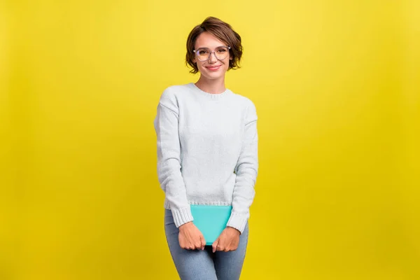写真の正魅力的なかわいいですオタク女性ホールド教科書着用アイウェアブルーセーター隔離された黄色の背景 — ストック写真