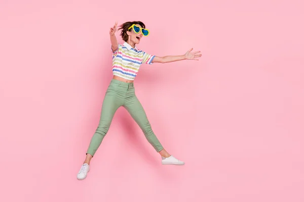 Full body profile side photo of young girl striped top open arms hug invite jump up sunglass isolated over pink color background.