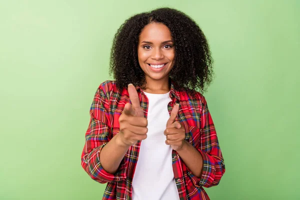 Photo of young charming african lady indicate fingers choice solution isolated over green color background.