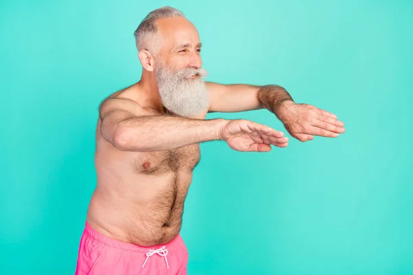 Profile photo of sporty pensioner man enjoy swim look empty space wear pink shorts isolated teal color background.