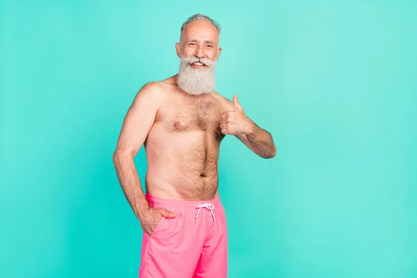 Photo of confident reliable old man raise thumb up approve solution wear pink shorts isolated teal color background.