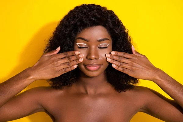若い美しい魅力的な積極的なアフロの女の子の写真は服を着ていない黄色の色の背景に隔離された頬にクリームを適用 — ストック写真