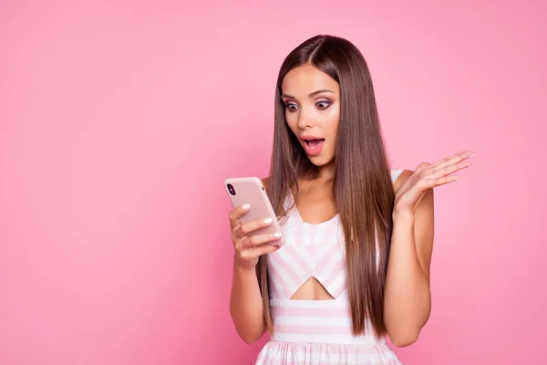 Photo of impressed funky woman wear striped dress reading modern device empty space isolated pink color background.