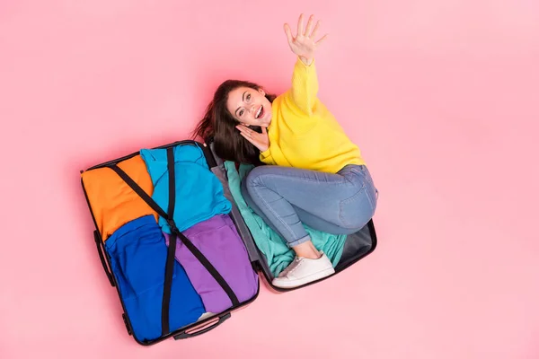 年轻快乐的女孩坐在行李箱上方的高角镜照片 准备在粉色背景下独立旅行 — 图库照片