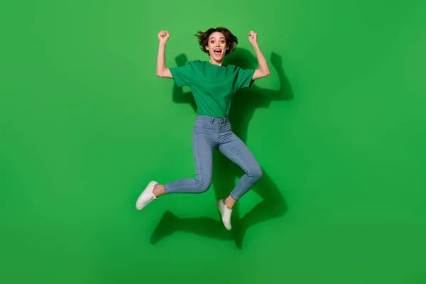 全身人像 心满意足的女孩跳起来举起拳头叫道 在绿色背景下孤立无援 — 图库照片