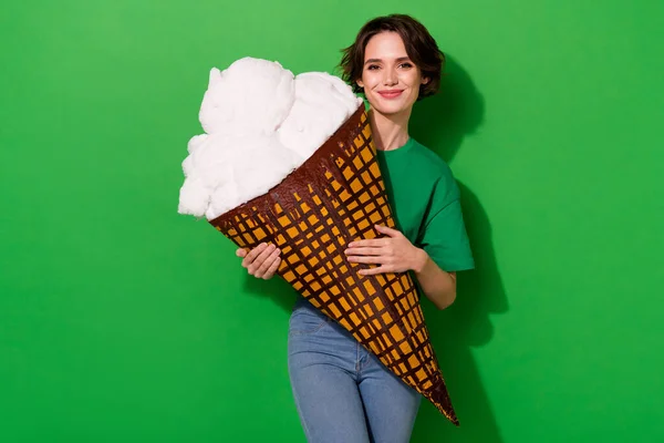 Photo of satisfied pretty person hold large ice cream look camera isolated on green color background.
