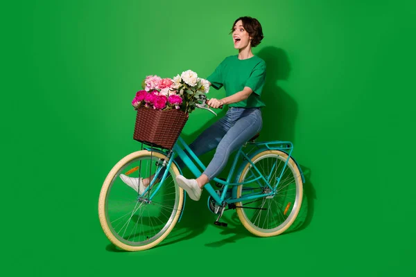 フル長さプロフィール写真の人のドライブバイク見る空のスペース新鮮な牡丹隔離された緑の色の背景 — ストック写真