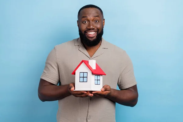 Portrait of cheerful friendly person hands hold small house toothy smile isolated on blue color background.