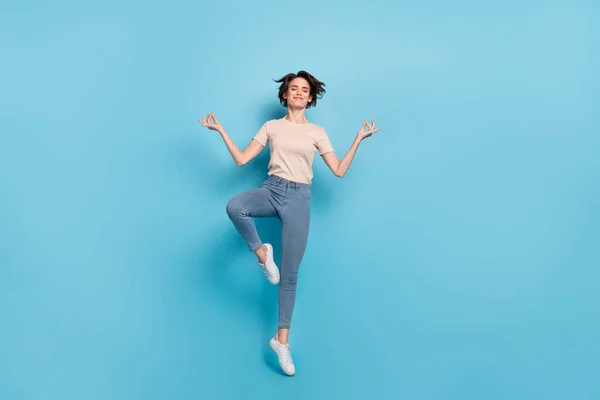 夢のようなかわいい女性の完全な長さの写真を着てベージュTシャツジャンプ高練習ヨガ隔離された青の背景 — ストック写真
