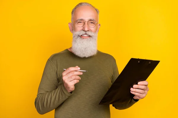 Photo of joyful old white beard man write wear eyewear green sweater isolated on yellow color background.