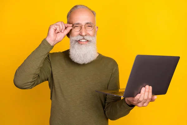 Photo of funny elder white beard man hold laptop wear eyewear green sweater isolated on yellow color background.