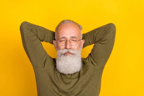 Photo of rest elder grey beard man hands head sleep wear eyewear green sweater isolated on yellow color background.