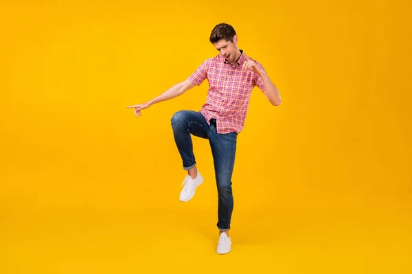 Full length photo of young man happy positive smile have fun dance party isolated over yellow color background.