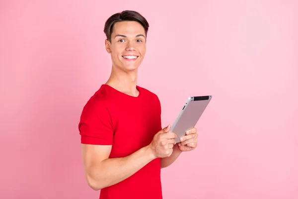 Profile side photo of young guy happy positive smile use tablet read browse online isolated over pink color background.