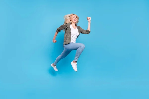フル長さボディサイズ写真幸せな女性ジャンプアップ実行中の高速隔離されたパステルブルーの背景 — ストック写真