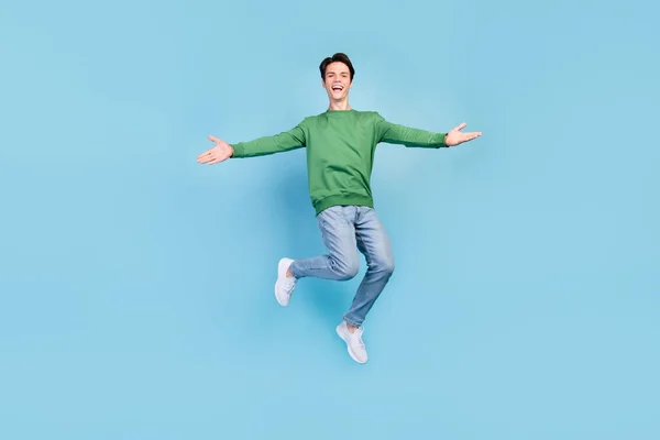 Full length body size photo guy jumping high inviting friends embracing smiling isolated pastel blue color background.
