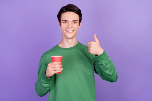 照片上年轻英俊的小伙子笑得很开心 照片上有一个大拇指的杯子 上面有紫色的背景 — 图库照片