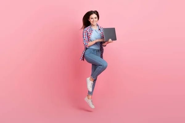 ピンク色の背景に孤立した彼女のネットブックで新しいプロジェクトに取り組んでビジネス女性をジャンプのフルサイズの写真 — ストック写真