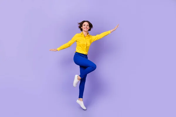 Full size photo of impressed young brunette lady jump wear shirt pants shoes isolated on purple background.