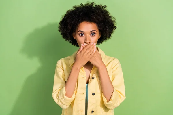 stock image Photo of shocked scared lady wear yellow denim jacket arms cover lips isolated green color background.