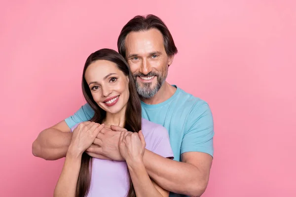 Portrait of two idyllic peaceful people embrace look camera isolated on pink color background.