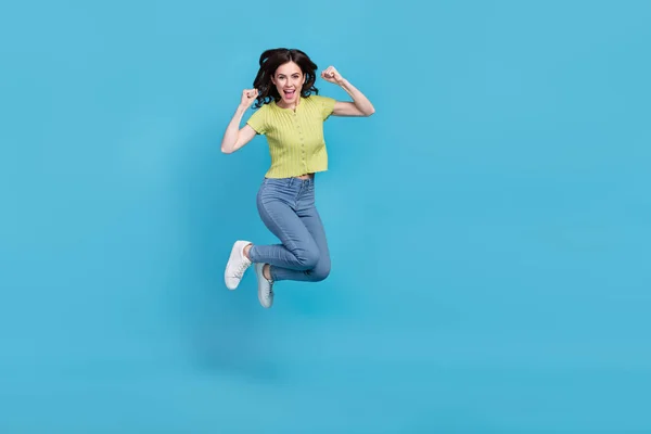 フル長いです写真の甘いですミレニアムブルネット女性ジャンプ大声で服Tシャツジーンズスニーカー隔離された青の背景 — ストック写真