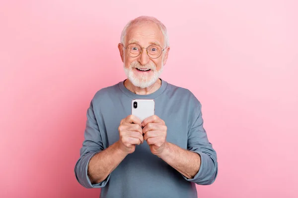 印象的な古いグレーのヘアドアの男の写真ピンクの色の背景に隔離された電話を着用アイウェアブルーのシャツを保持 — ストック写真