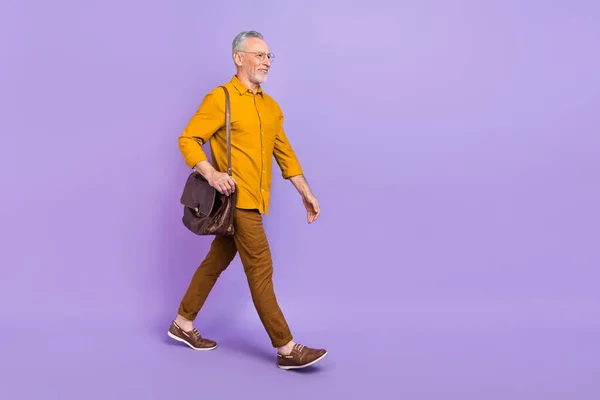 Full body profile side photo of senior man walk look empty space representative isolated over violet color background.