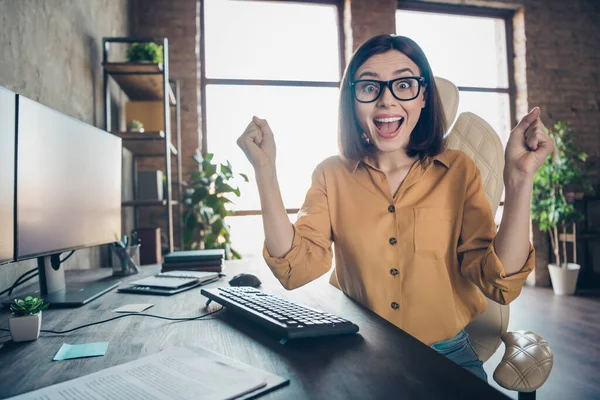 Portrait of attractive cheerful lucky crazy girl cyber editor celebrating great attainment at workplace workstation indoors.