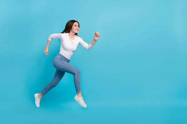 Photo of charming pretty lady dressed white shirt jumping high running empty space isolated blue color background.