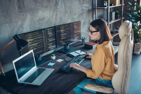 Profile side view portrait of attractive focused skilled girl web developer using laptop at workplace workstation indoors.