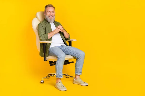 Full body portrait of cheerful aged person sitting chair have good mood isolated on yellow color background.