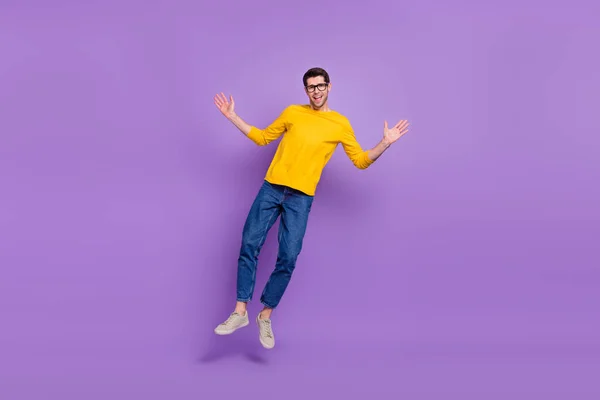 全长照片 快乐无忧无虑的男人跳了起来 穿着黄色衬衫 用紫罗兰色衬托着斜纹棉布 — 图库照片