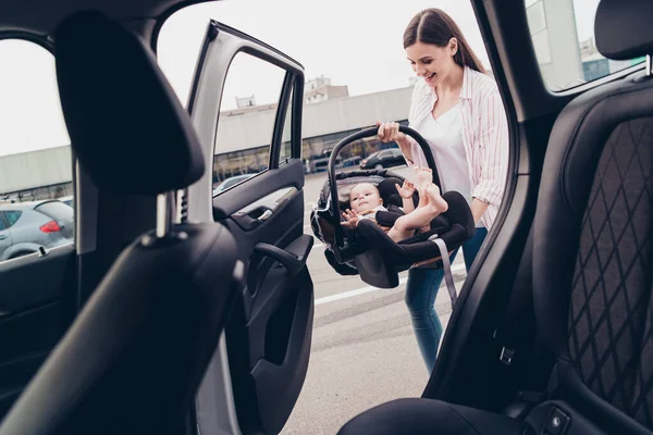 Portrait of positive lady hands hold toddler sitting baby safety chair street outside car salon.