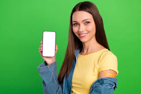 Portrait of positive pretty person hold demonstrate empty space telephone screen isolated on green color background.