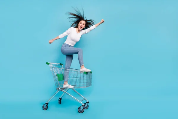 全长照片 一个快乐的神奇女人坐着推车跑去买蓝色背景的特价商品 — 图库照片