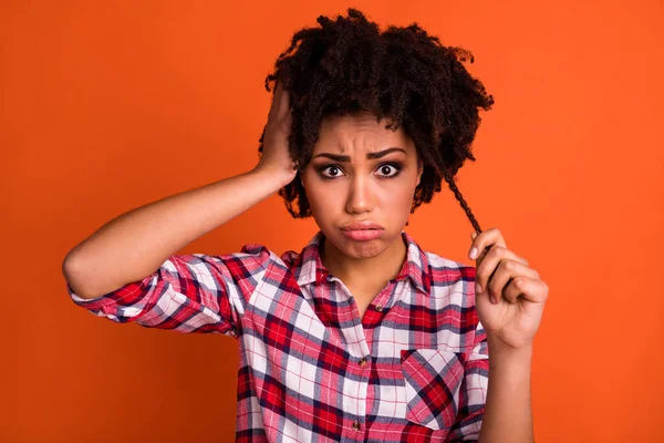 Photo of offended upset lady dressed checkered shirt arm head holding hair curl isolated orange color background.