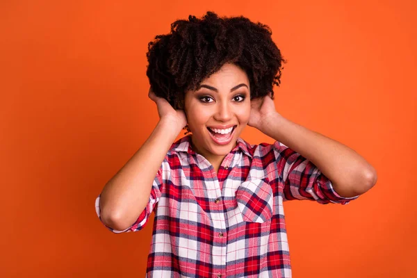 Portrait of cheerful excited person hands touch wavy hairdo toothy smile isolated on orange color background.