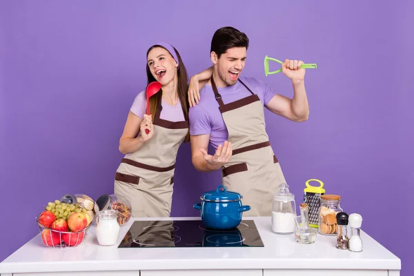 Photo of funky pretty boyfriend girlfriend dressed chef singing kitchen microphones isolated purple color background.