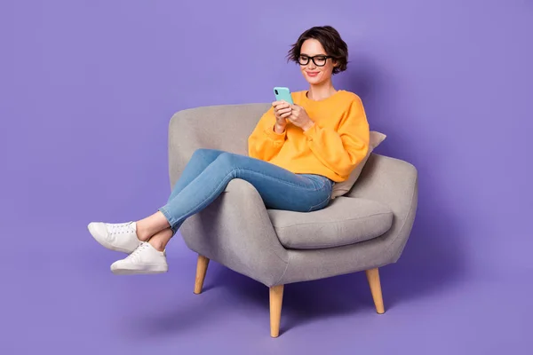 魅力的な陽気な女の子の肖像を使用して座っているデバイス通信ポストビデオ絶縁以上紫ライラック色の背景 — ストック写真