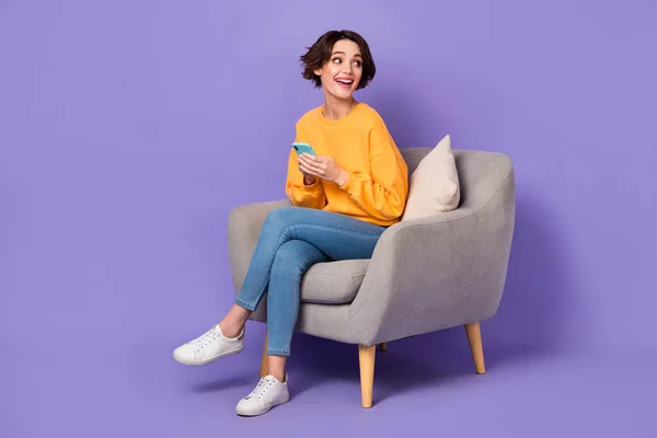 魅力的な陽気な流行の女の子の肖像画椅子に座っているガジェットを使用して見てコピースペースのアイデア孤立以上紫ライラック色の背景 — ストック写真
