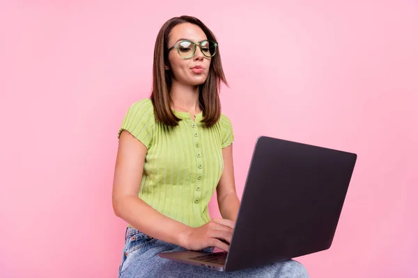 悲しいブルネットの千年紀の女性の写真ノートパソコンを書くピンクの色の背景に隔離された緑のTシャツの眼鏡を着用 — ストック写真